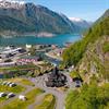 Lothepus Camping i Odda med stavkyrkje, hytter og campingplassar ved Sørfjorden, omgitt av snøkledde fjell i Hardanger