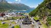 Stavkyrkjebygget med Langhuset ved Lothepus Camping i Odda, Sørfjorden og snødekte fjell bak, frå lufta.