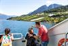 Far peiker mot frukthagar i fjordliene for barna sine på dekket under fjordcruise på Hardangerfjorden.