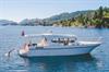 The boat Pilagutt cruising in the Hardangerfjord, with sunshine, blue water, and people swimming. A perfect fjord cruise experience.