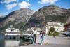 To kvinner går på kaia i Eidfjord med cruisebåten Fjorddrott fortøydd bak og bratte fjell i bakgrunnen.
