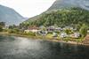 En liten campingplass ved en elv, omgitt av grøntområder.