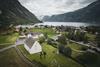 Et dronebilde av Eidfjord gamle kirke, med fjorden i bakgrunnen.