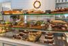 A display counter filled with sandwiches, cakes, and a variety of baked goods.