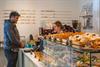 A man standing at the cashregister paying for some baked goods.