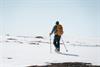 Ein Mann auf Schneeschuhen geht bei sonnigem Wetter bergauf durch den Schnee der Hardangervidda.
