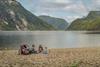 A family of four sitting on a sandy beach by the Eidfjord lake.