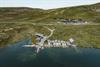 A drone shot with the harbour in the foreground and Halne Fjellstugu in the background.