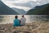 Ein Paar sitzt am Sandstrand am Eidfjord-See.