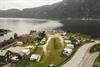 Eit dronebilete av campingplassen med fjorden og fjella i bakgrunnen.