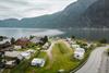 Eit dronebilete av campingplassen med fjorden og fjella i bakgrunnen.