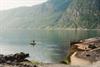 Stranden Kråkeskarvet, med en person som hopper fra stupebrettet og ut i fjorden. Mange mennesker soler seg og svømmer.