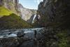 Ein Mann steht am Flussufer und blickt auf den Wasserfall.