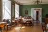 Grüner Salon im Haupthaus von Halsnøy Kloster mit Sofa, Porträt im Goldrahmen und Sonnenlicht durch hohe Fenster.