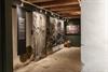 Ausstellung auf Halsnøy Kloster mit großen Fotos archäologischer Ausgrabungen, Steinboden und alten Tonkrügen.