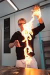 A student wearing safety goggles holds up a large flame during a fire show demonstration at KraftLaben science centre in Odda, Hardanger.
