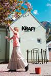 A child creates a giant soap bubble outdoors at KraftLaben's science park in Odda, Hardanger, with cherry blossoms and blue sky in the background.
