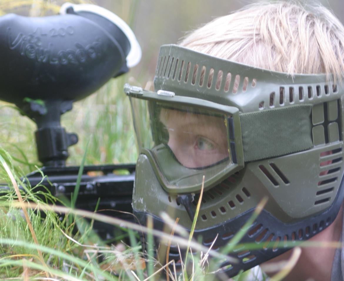 Paintballspelare i ansiktsmask i gräset