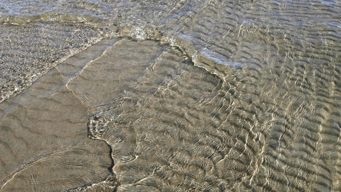 Sandstranden formas av vågorna