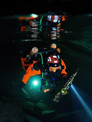Jazzathlete on a dive towards the concert venue in Plura Cave with his saxophone