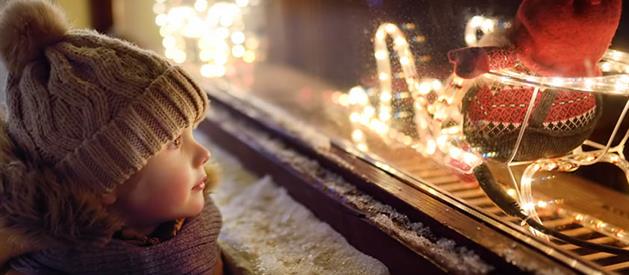 Flicka som tittar i skyltfönster till jul